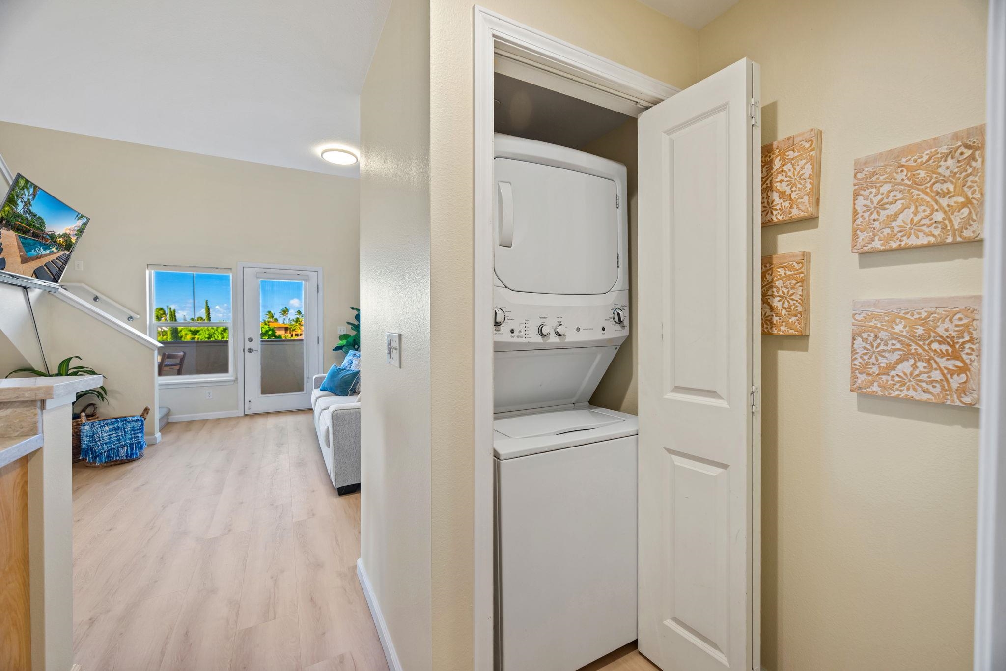 Stacked washer and dryer in an open closet, with the condo living area visible beyond.