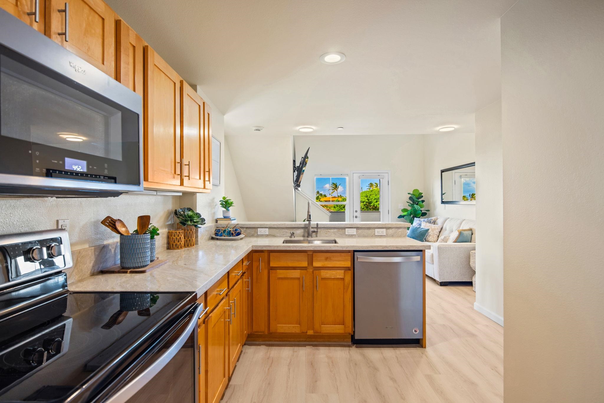 Kitchen with warm wood cabinets and stone counters opening onto a living area.