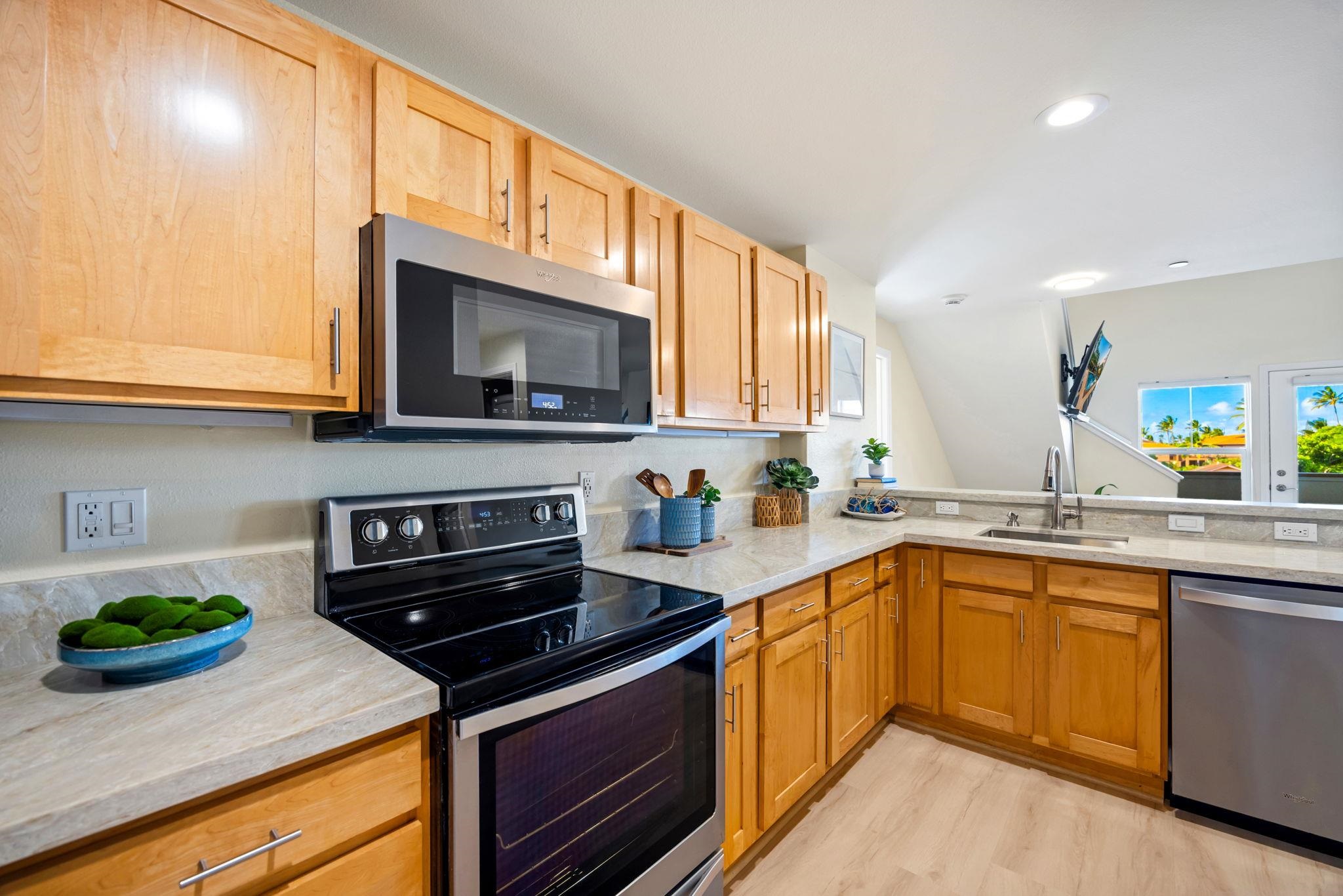 Kitchen with honey-colored cabinets, stone counters, black range, and stainless dishwasher.