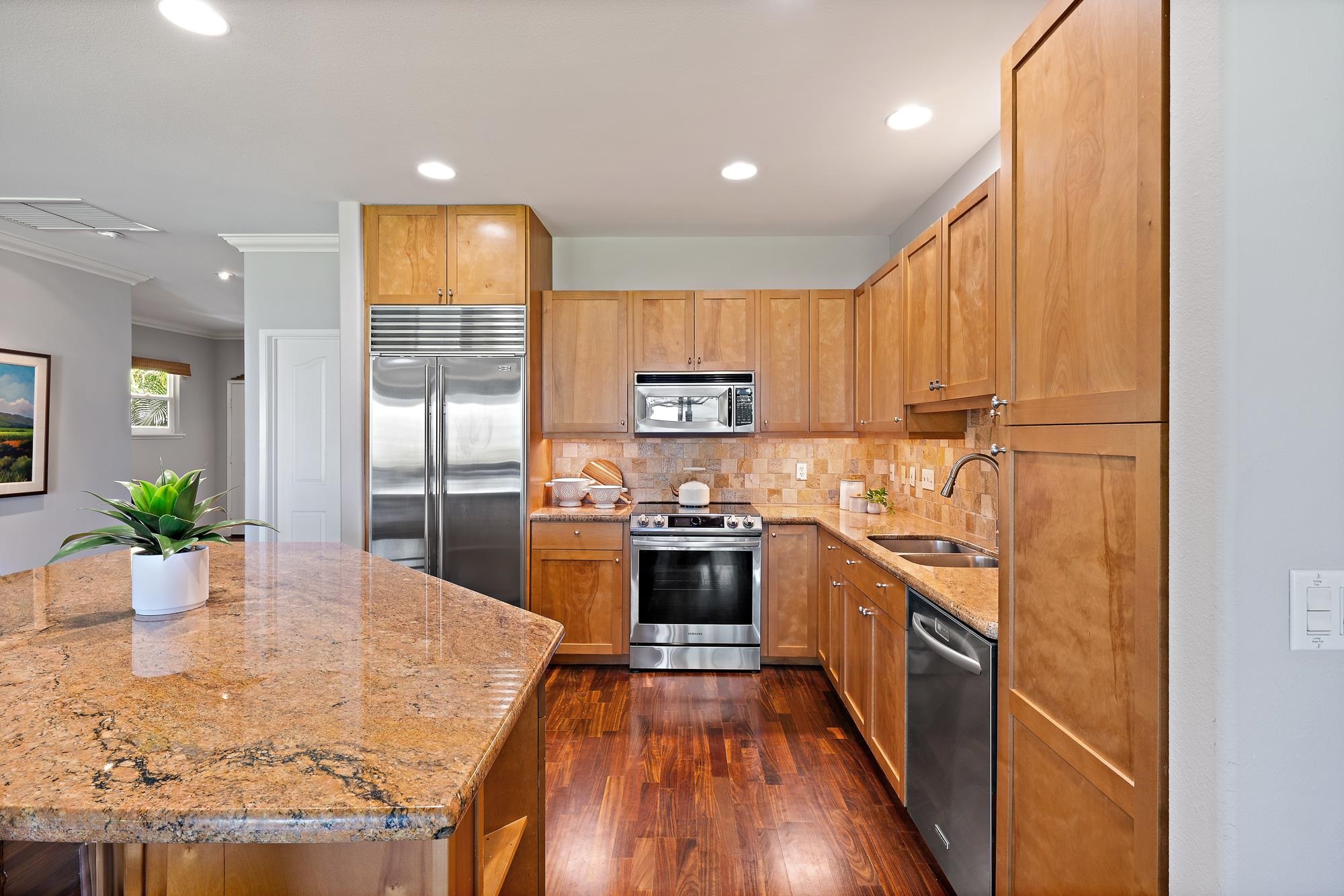 Kitchen with warm wood cabinets, a granite island, and stainless steel appliances.