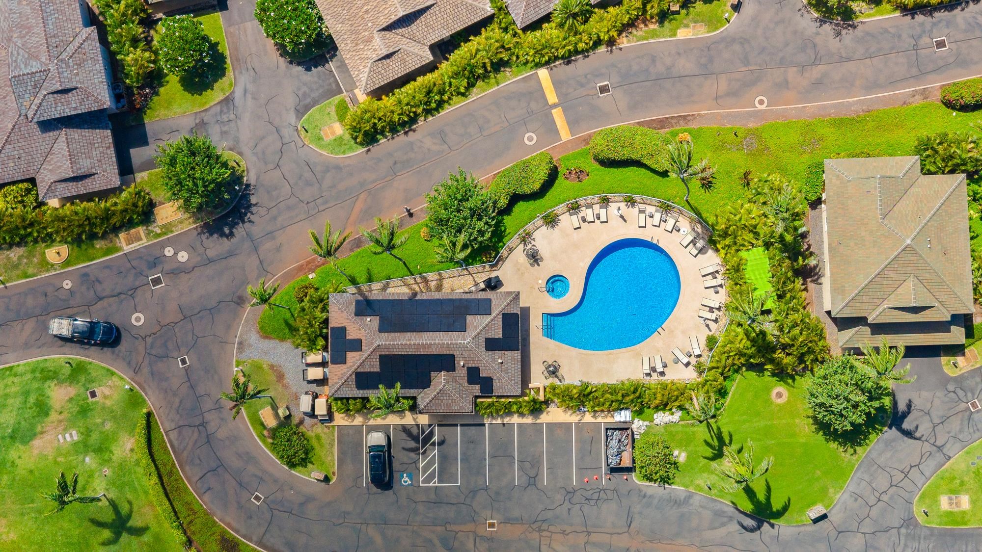 Aerial view of a landscaped residential complex with a kidney-shaped pool and parking.