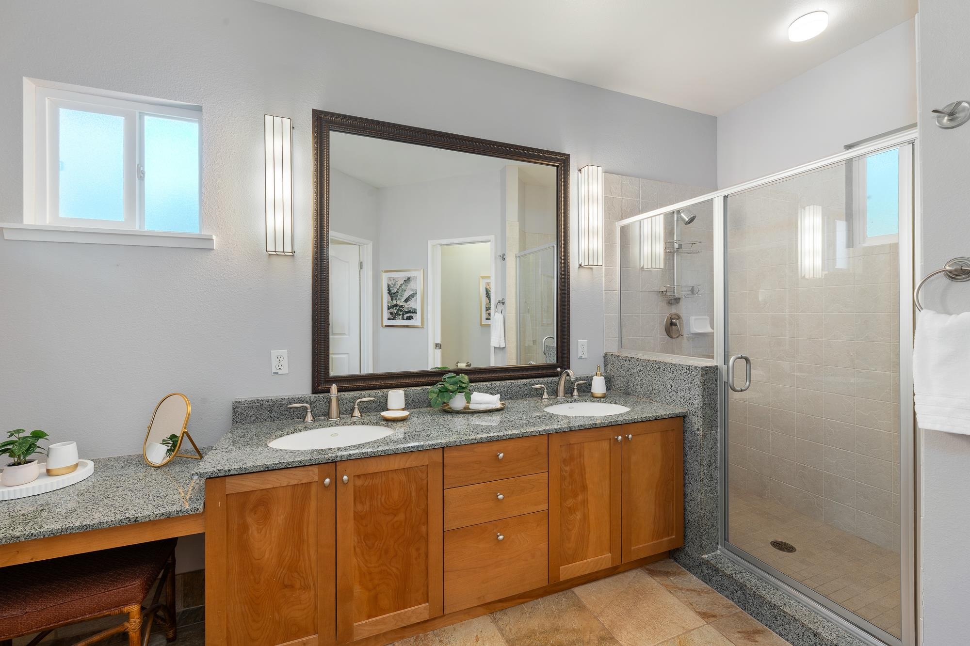 Bathroom with a double-sink granite vanity and glass-enclosed tiled shower.