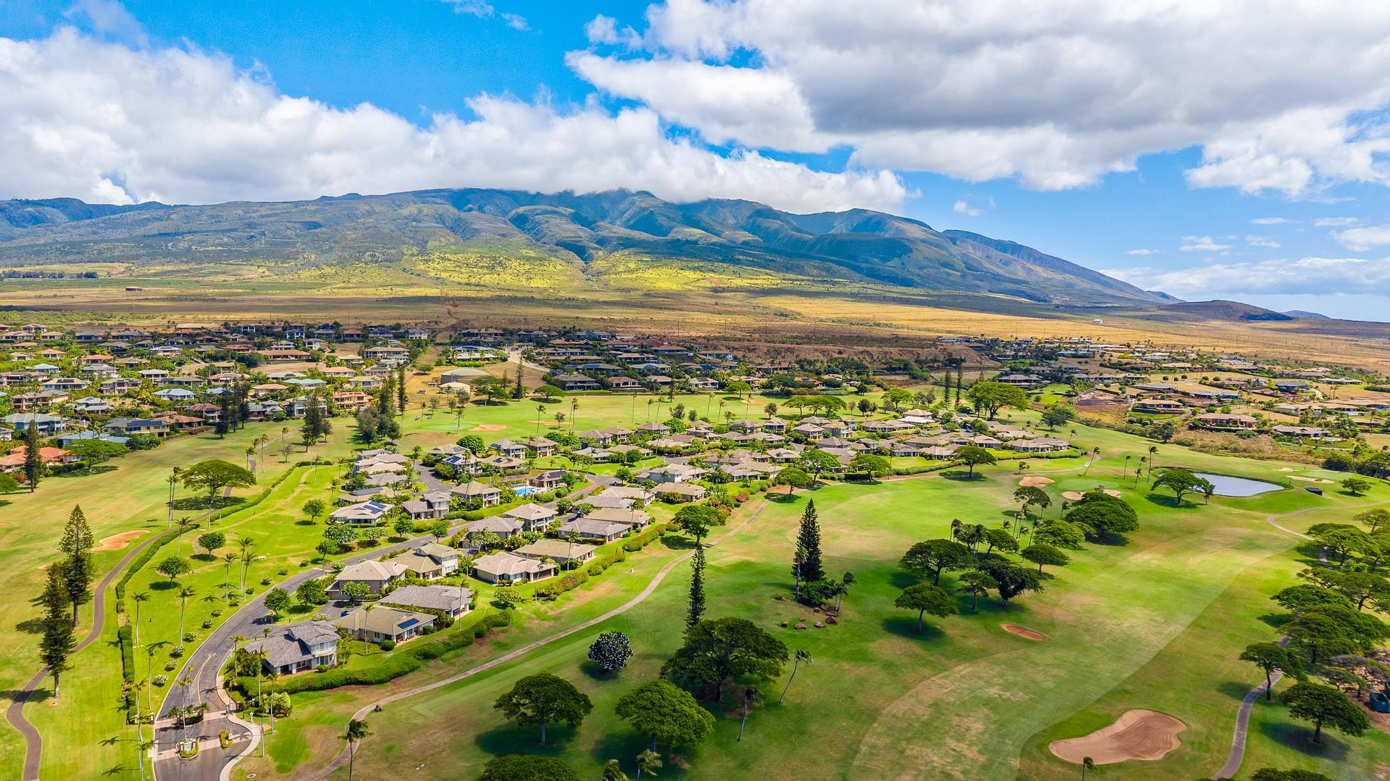 Aerial view of homes and golf course fairways with mountains in the distance.