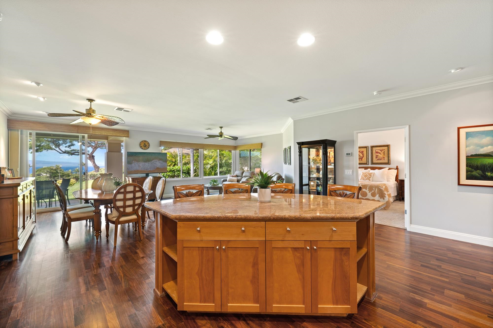 Open-plan kitchen and dining area with a large wood island and ocean views through sliding glass doors.