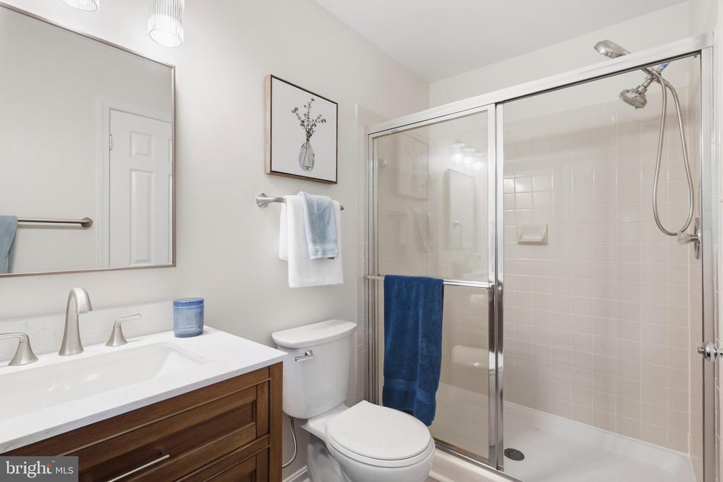 Bathroom with a dark wood vanity and glass-enclosed tiled shower.
