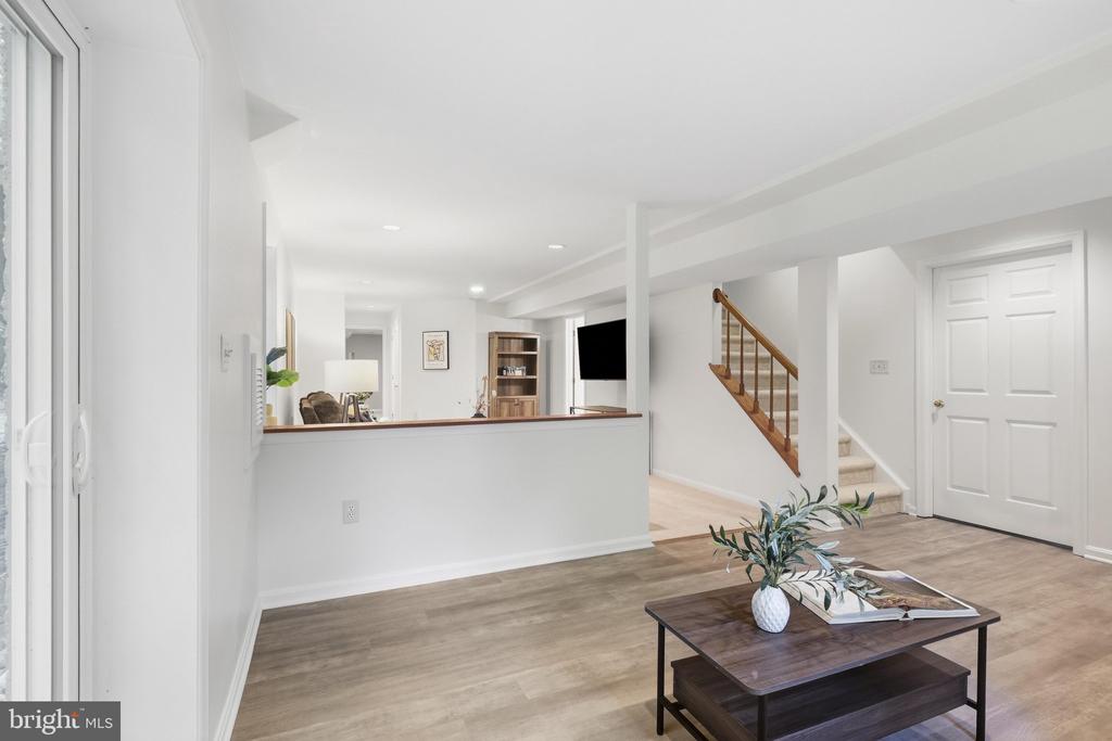 Living room with light wood floors, a dark coffee table, and an open staircase.