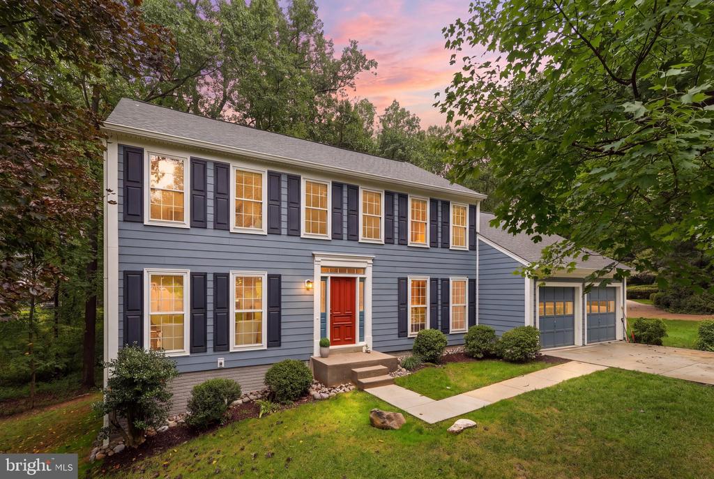Two-story gray house with a red front door and attached two-car garage at dusk.