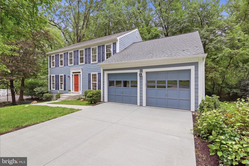 Blue-gray two-story home with an orange front door, attached two-car garage, and broad driveway.