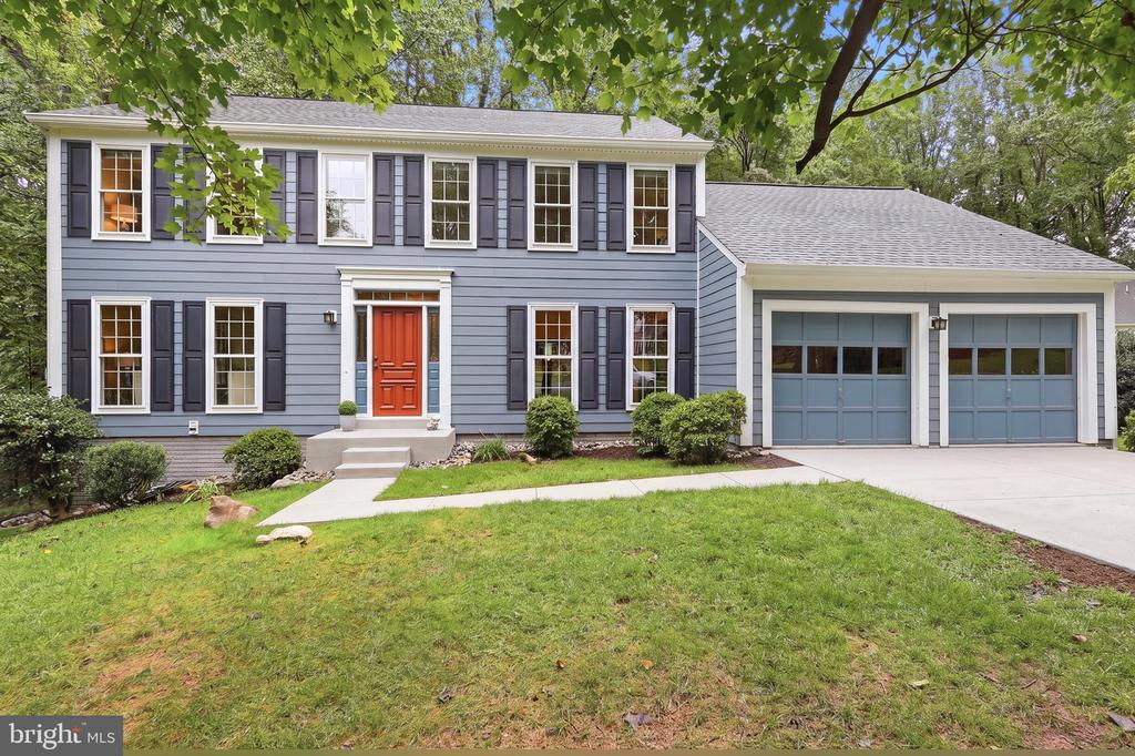 Blue two-story house with a red front door, dark shutters, and an attached two-car garage.