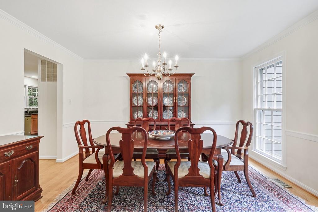 Dining room with a dark wood table, glass-front china cabinet, chandelier, and patterned rug.
