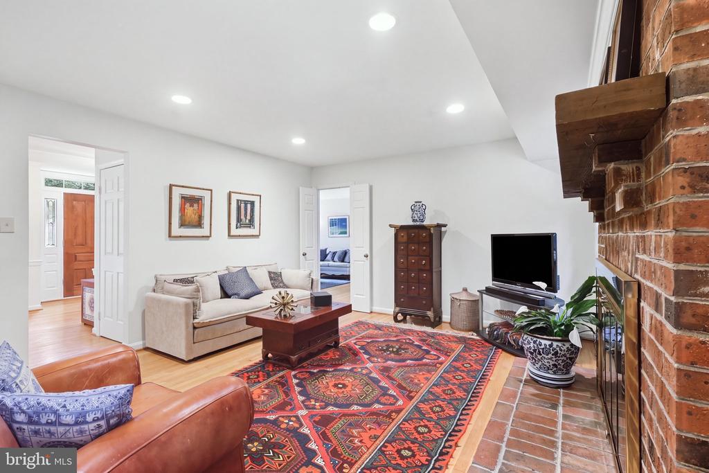 Living room with a brick fireplace, beige sofa, leather armchairs, and colorful patterned rug.