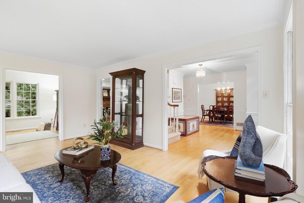 Living room with a blue patterned rug, glass-front cabinet, and open views into adjoining rooms.