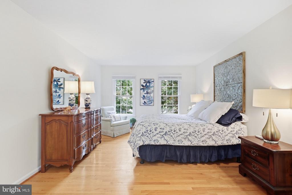 Furnished bedroom with a floral bedspread, dark wood furniture, and two windows.