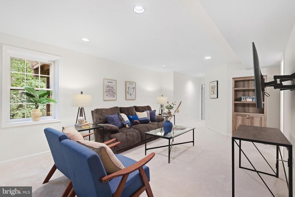 Furnished living room with a brown sofa, blue chairs, and a wall-mounted television.
