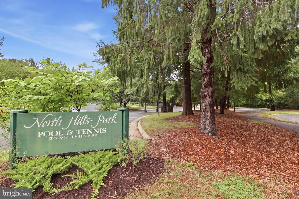 North Hills Park sign beside a tree-lined road, marking pool and tennis amenities.