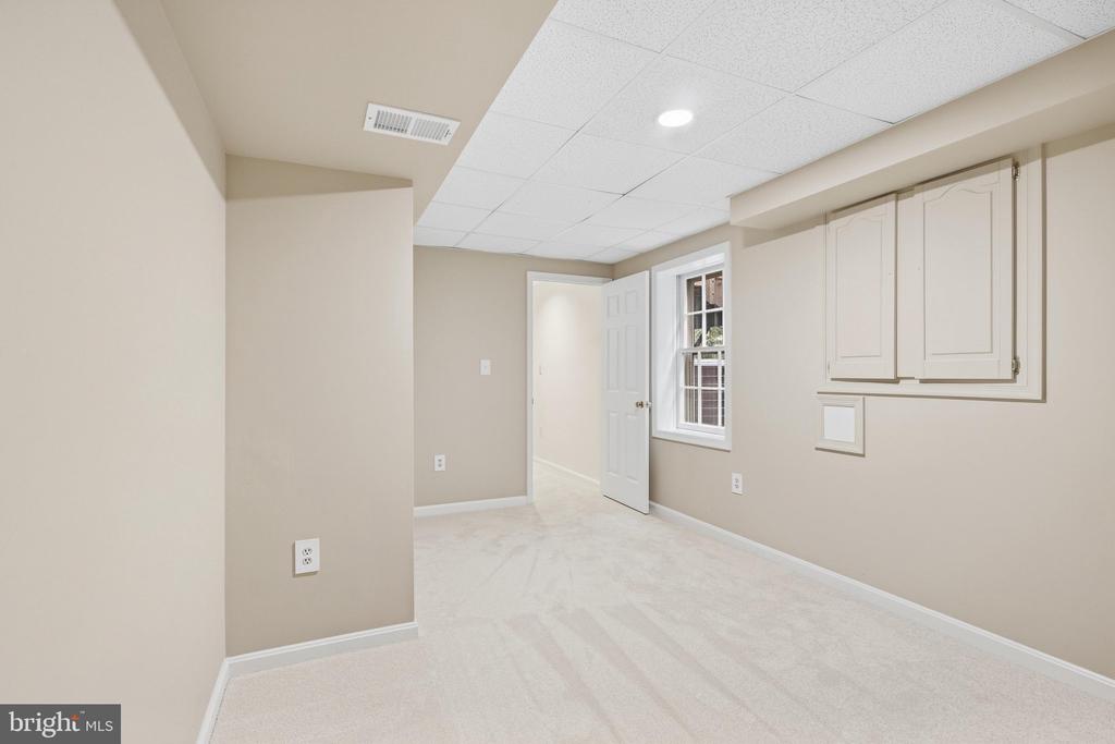 Unfurnished carpeted room with built-in cabinets, a window, and an open doorway.