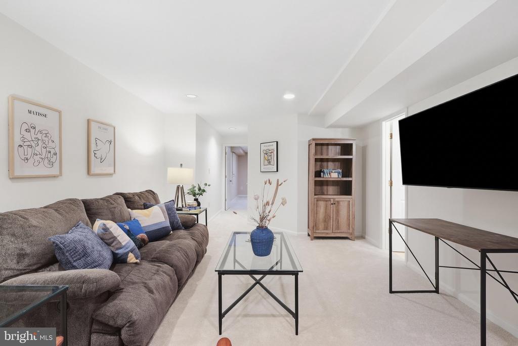 Furnished living room with a brown sectional, glass coffee table, wall-mounted television, and wood cabinet.