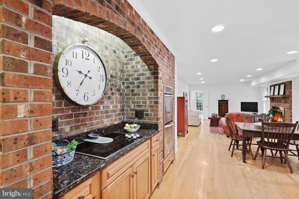 Open-plan kitchen and dining area with a brick arch, granite counters, and adjoining fireplace.
