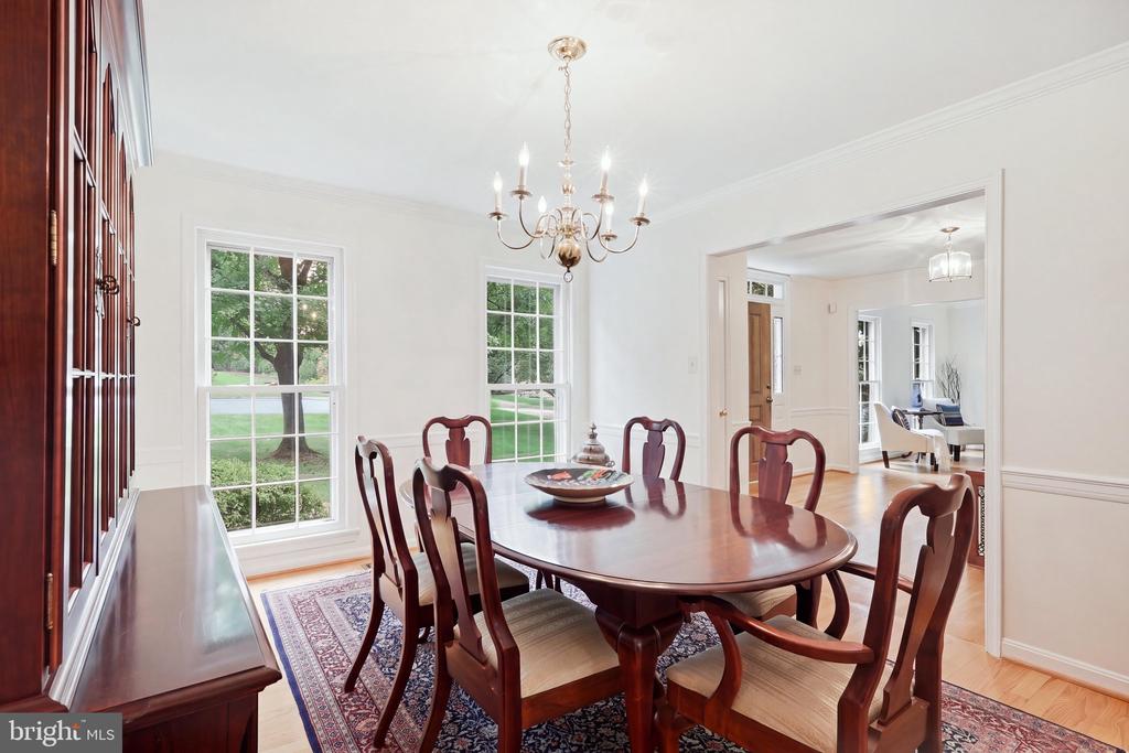 Dining room with a dark wood table, chandelier, built-in cabinetry, and large windows overlooking the lawn.