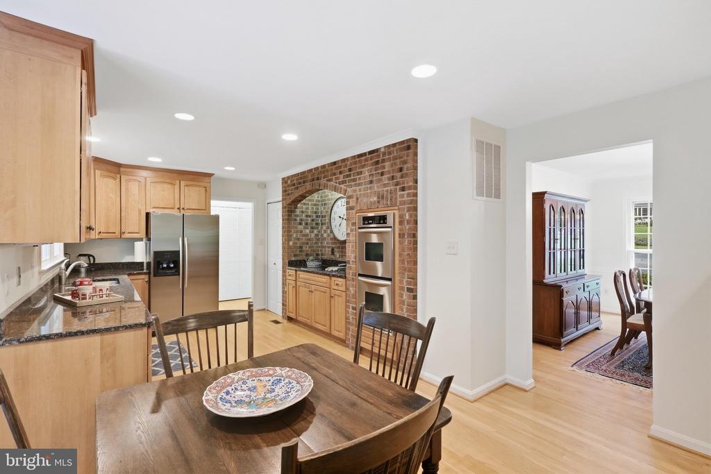 Kitchen and dining area with light wood cabinets, granite counters, and a brick cooking alcove.