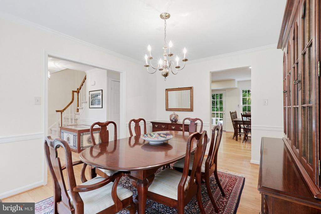 Dining room with a polished wooden table, chandelier, patterned rug, and built-in glass-front china cabinet.
