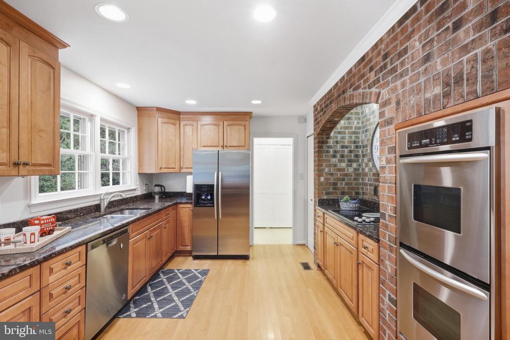 Kitchen with wood cabinets, stainless steel appliances, dark counters, and a brick oven alcove.
