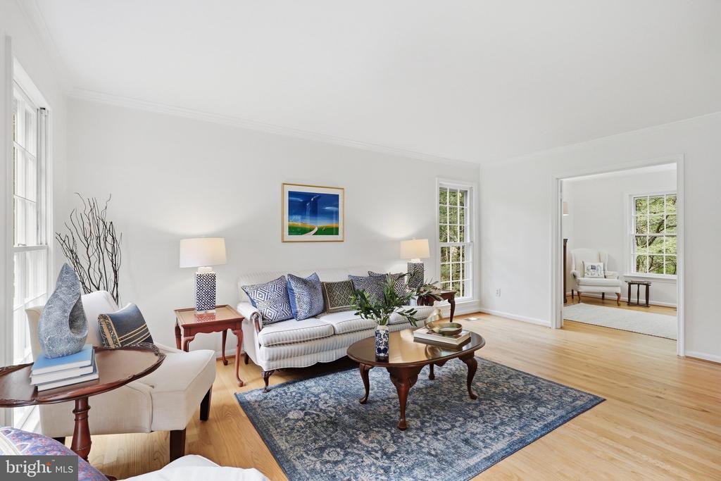 Staged living room with a white sofa, blue patterned rug, and adjoining sitting room.