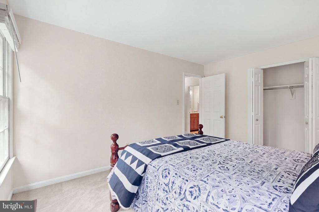 Bedroom with blue-and-white patterned bedding, a large window, and an open closet.