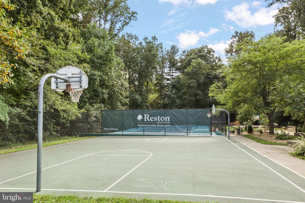 Community basketball court with hoops at both ends and a Reston Association banner along the far fence.