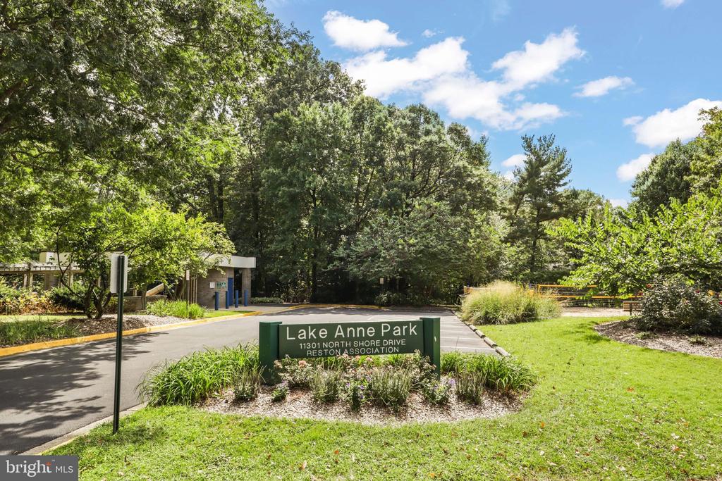 Lake Anne Park entrance sign beside a tree-lined drive and landscaped lawn.