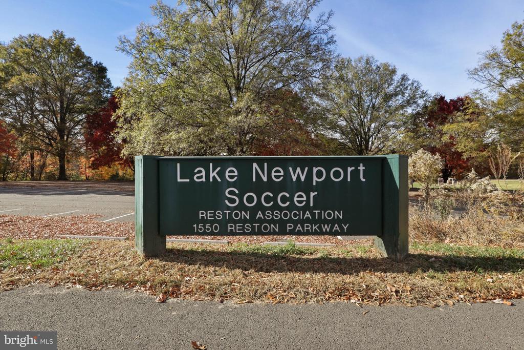 Lake Newport Soccer sign beside a parking area, surrounded by autumn trees.