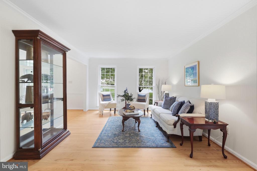 Bright living room with a blue rug, white sofa, and glass-front wooden display cabinet.