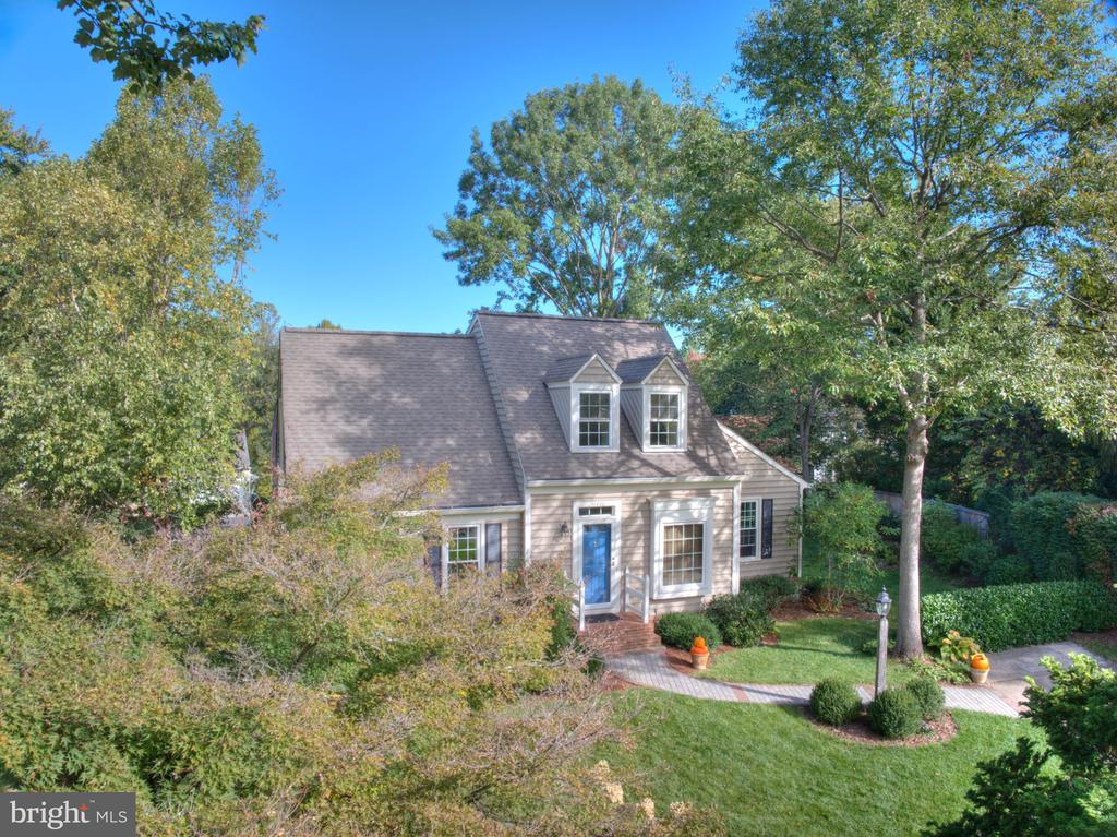 Elevated view of a two-story home with a steep roof, blue front door, and landscaped yard.