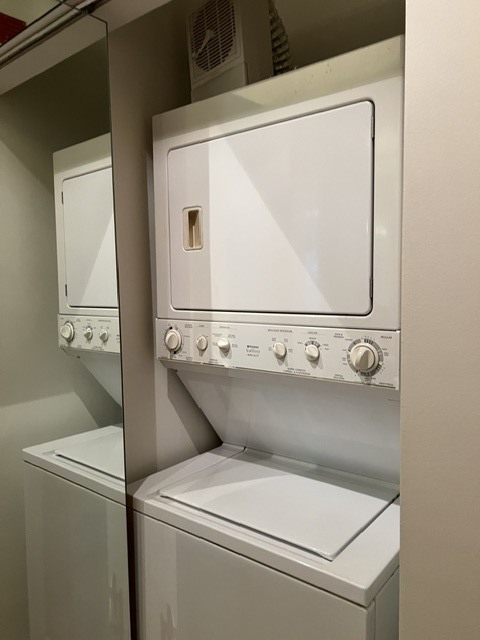 Stacked washer and dryer in a mirrored laundry closet.