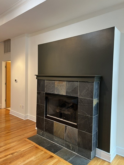 Living room with a dark stone fireplace and honey-toned hardwood floors.