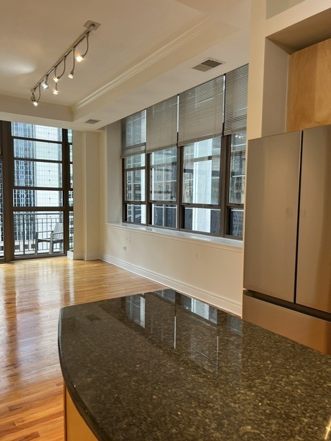 Kitchen with a dark granite island, hardwood floors, and tall windows overlooking nearby buildings.