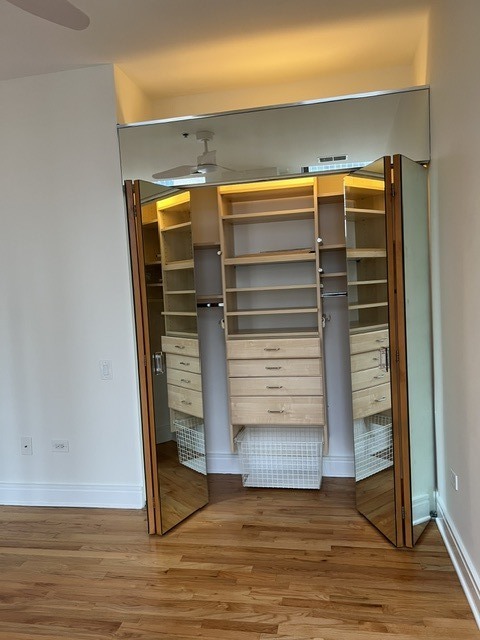 Walk-in closet with built-in shelves, drawers, and mirrored folding doors.
