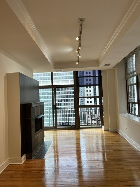 Living room with hardwood floors, a fireplace, and large windows overlooking downtown buildings.