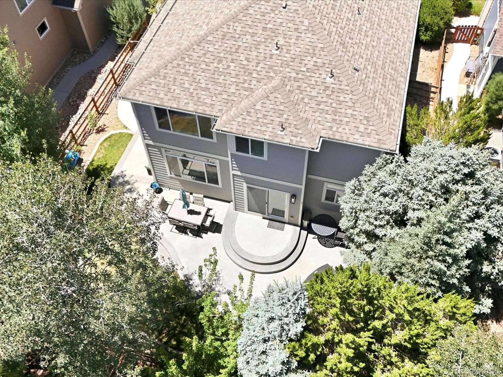 Aerial view of a gray two-story house with a curved patio and outdoor dining area.