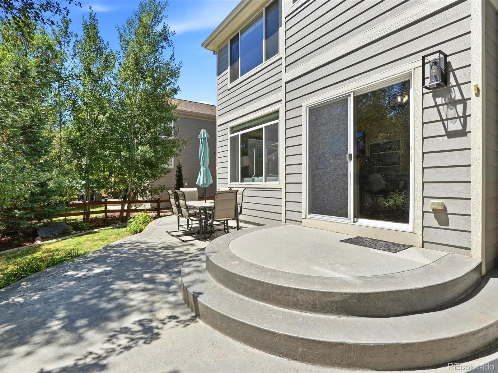 Home exterior with a curved raised patio, sliding glass doors, and an outdoor dining set.