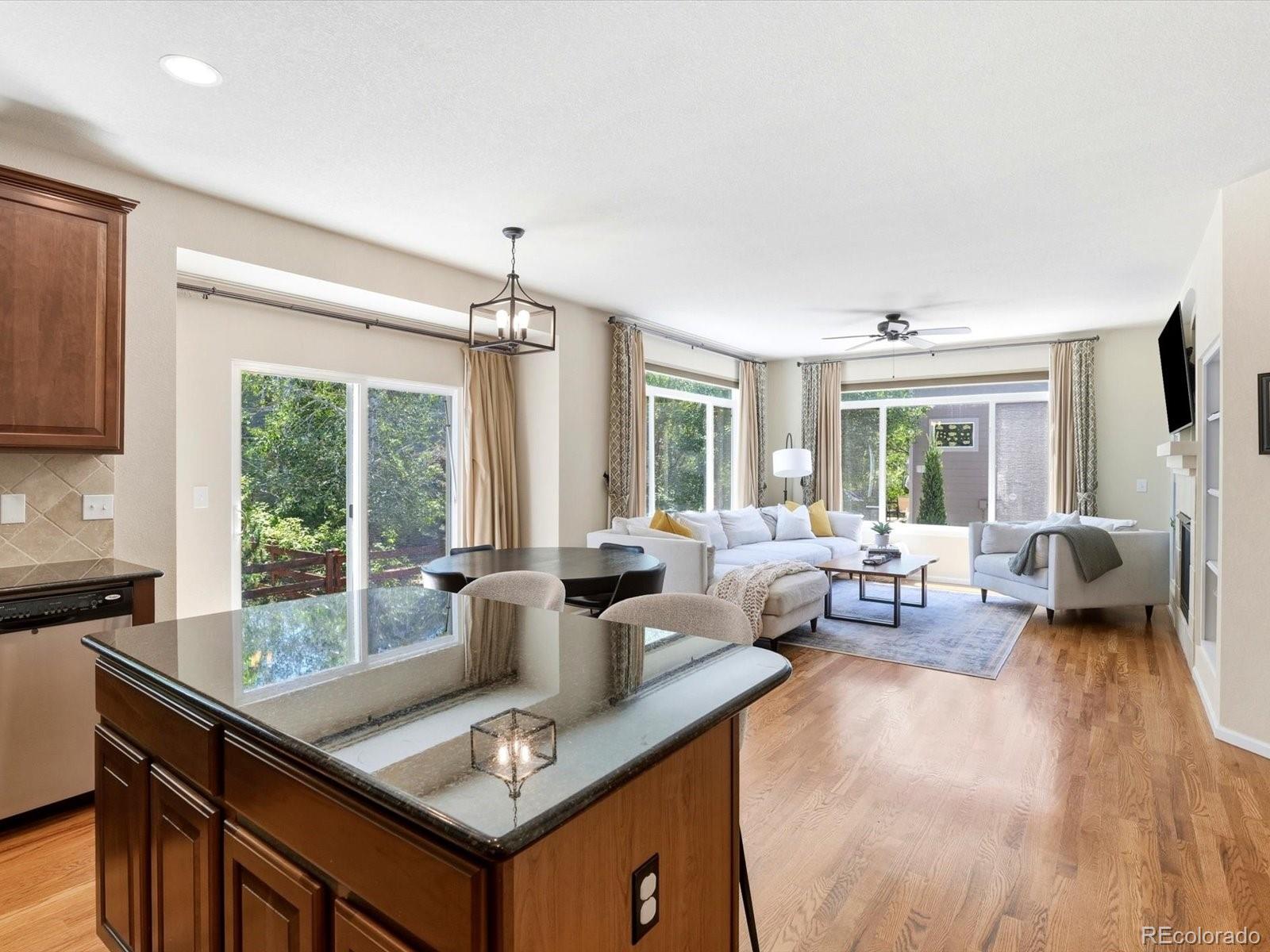 Open-plan kitchen and living room with a large island, hardwood floors, and a white sectional by broad windows.