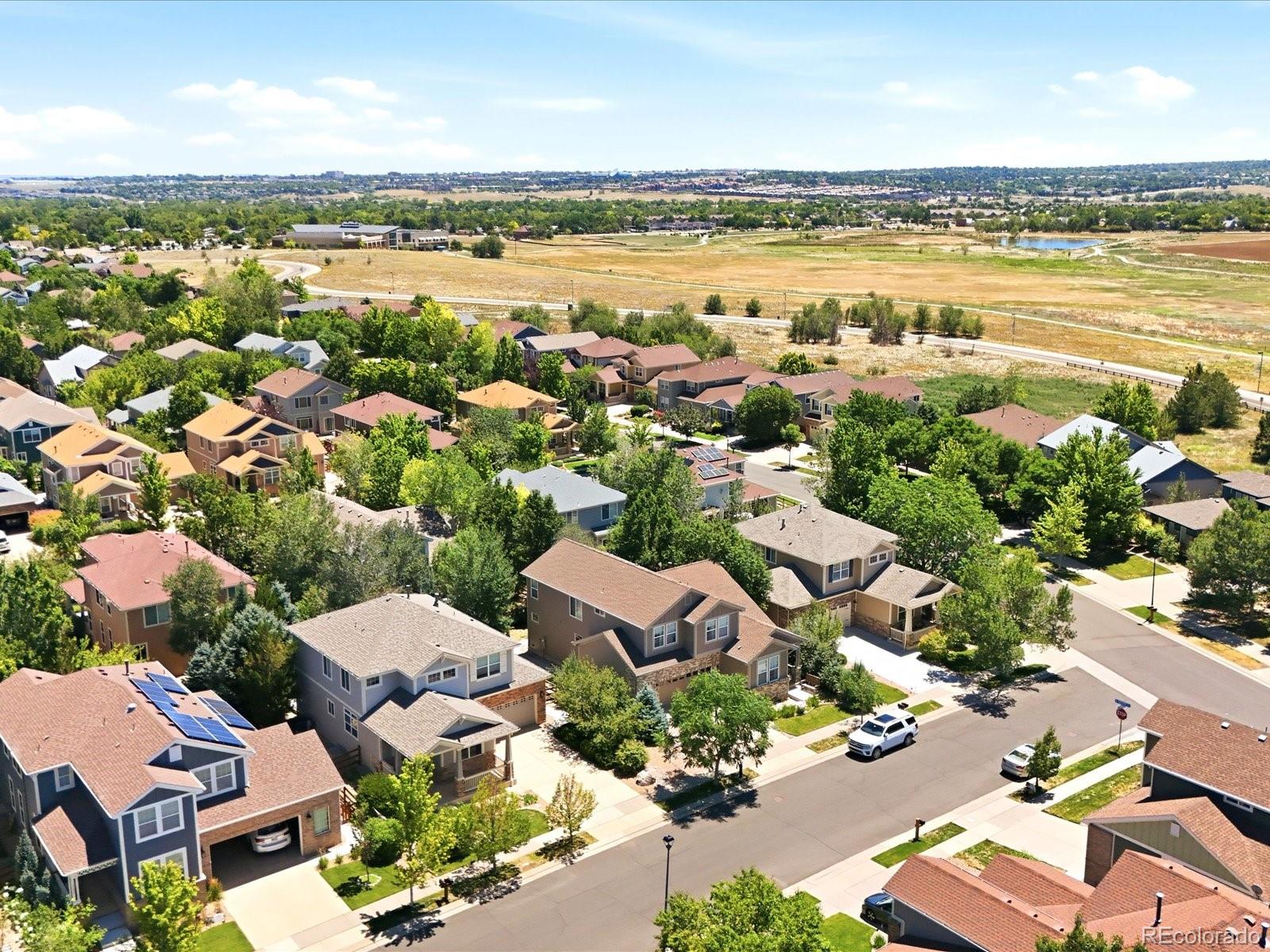 Aerial view of a residential neighborhood beside open fields and a small pond.