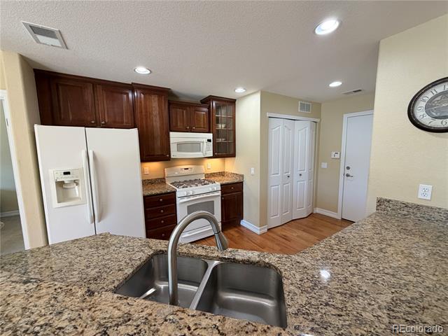 Kitchen with dark wood cabinets, stainless steel appliances, and granite counters around a double-basin sink.