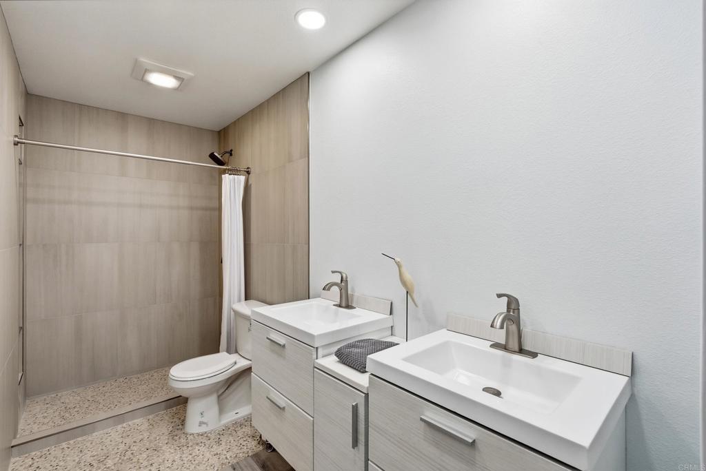 Bathroom with a tiled walk-in shower and double white vanities.