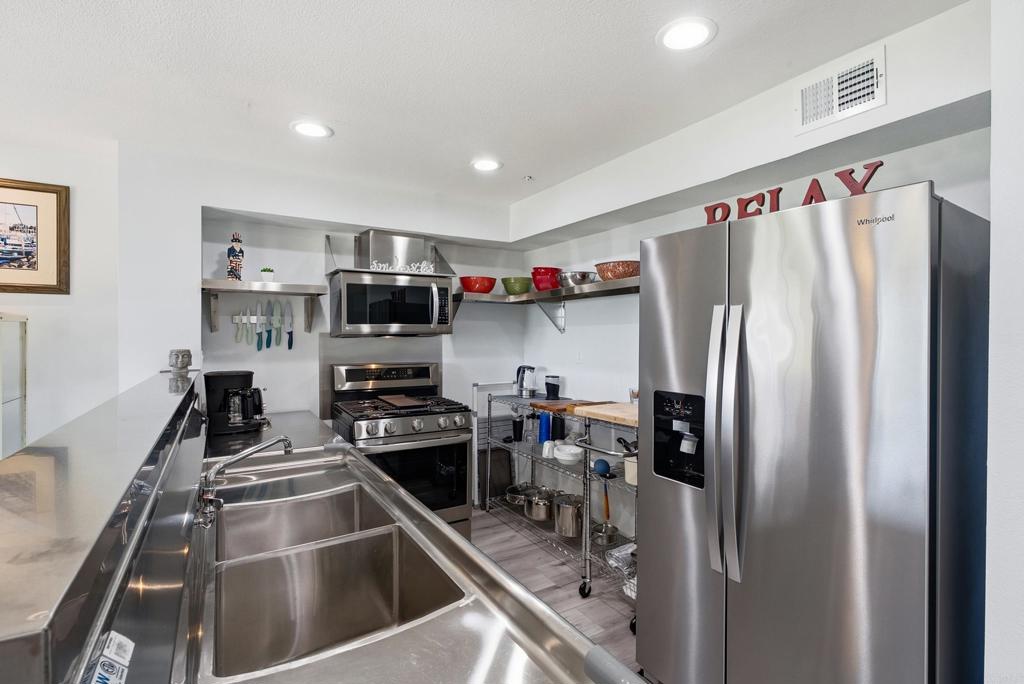 Kitchen with stainless-steel appliances, a deep sink, open shelves, and a rolling metal prep cart.