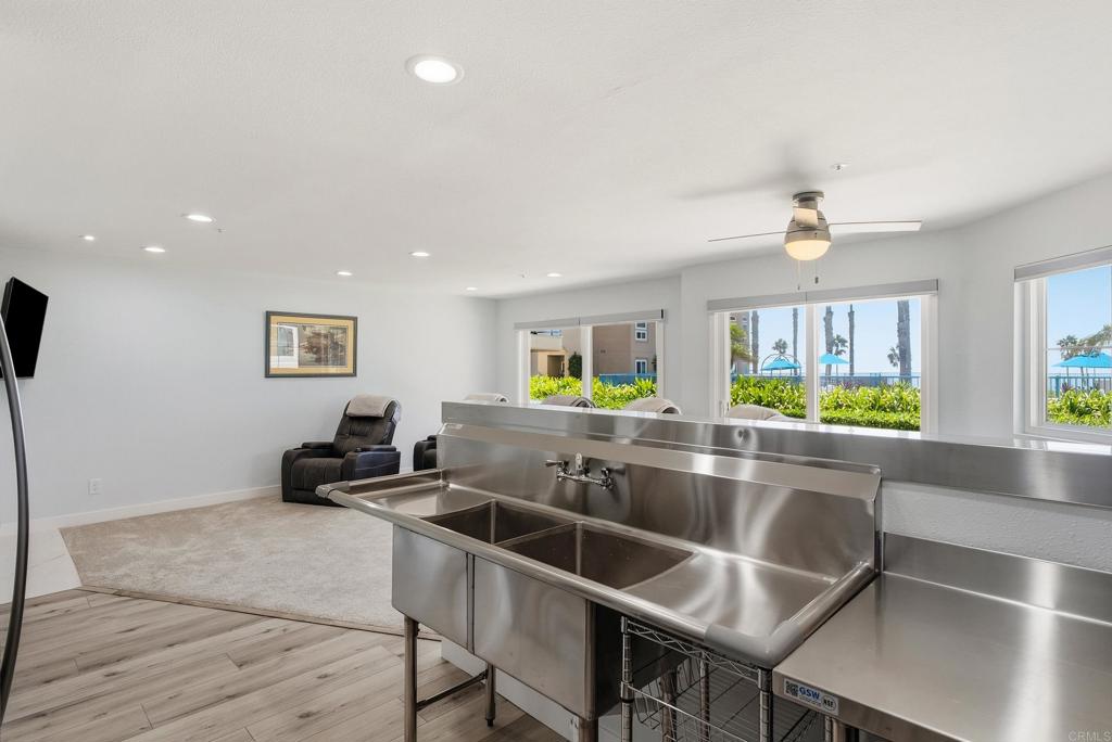 Bright interior with a large stainless steel sink, sitting area, and windows overlooking the ocean.