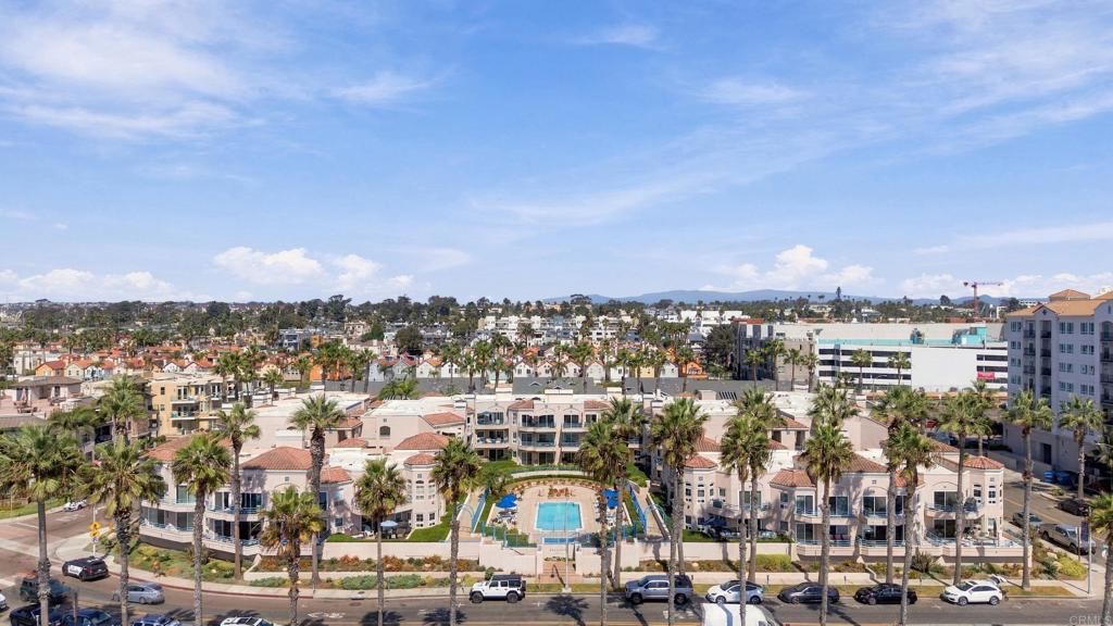 Aerial view of a residential complex with a central pool and palm-lined streets.