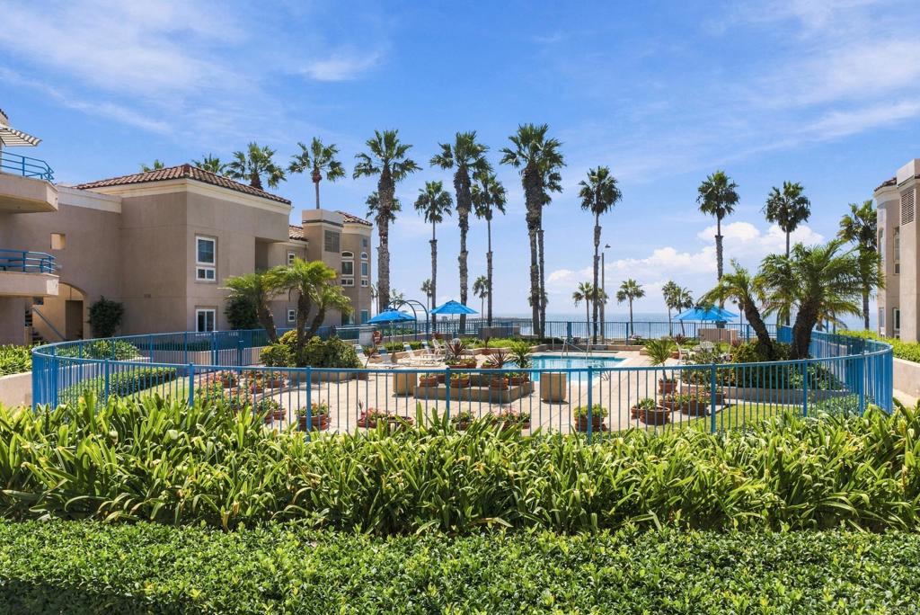 Condominium pool courtyard with palm trees and the ocean beyond.
