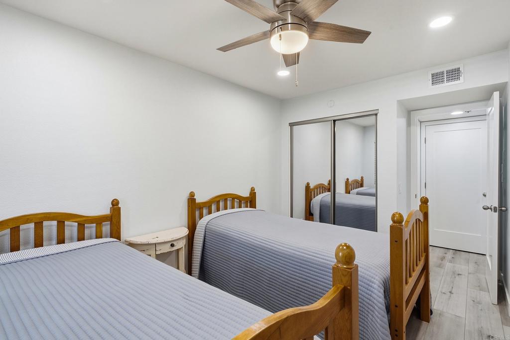 Bedroom with two wooden twin beds, mirrored closet doors, and a ceiling fan.
