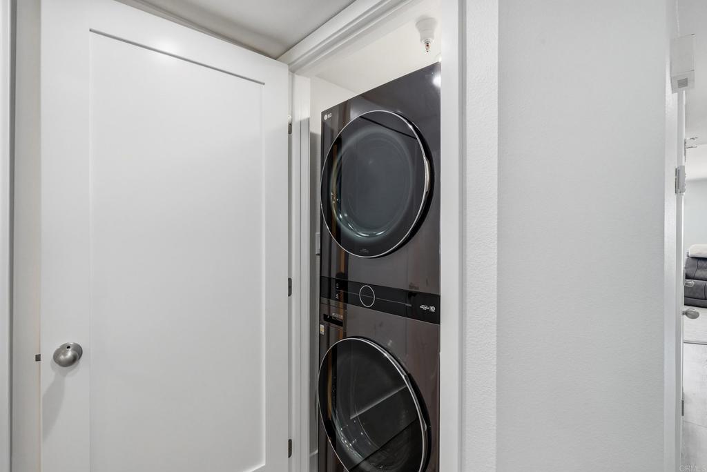Laundry closet with a stacked dark front-loading washer and dryer.